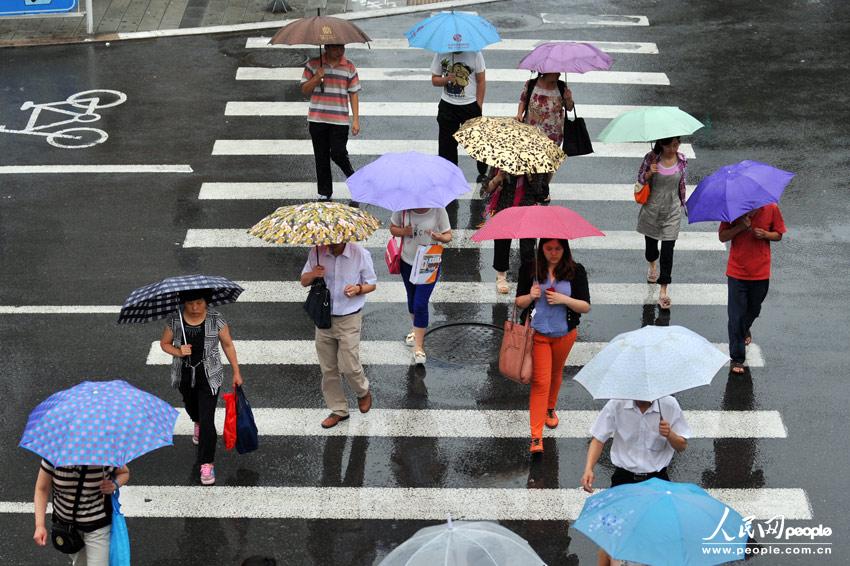 2013年7月9日,北京,路人打伞在雨中前行.(人民网记者 翁奇羽 摄)