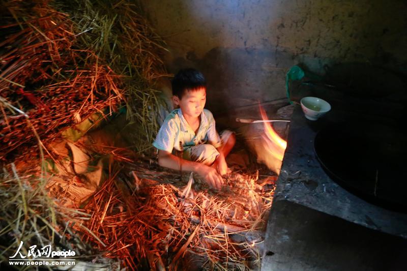 9月10日，河南西华县，11岁的肖楠（化名）帮奶奶烧火做饭。妈妈外出打工已经5年没有回来过，爸爸只在爷爷过世的时候回来过一次，肖楠与奶奶相依为命。(人民网记者 宋芳鑫 摄)