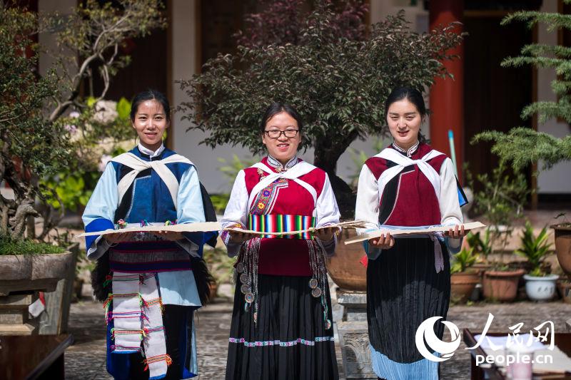 三名纳西族女孩向活动参与者展示纳西族的传统服饰