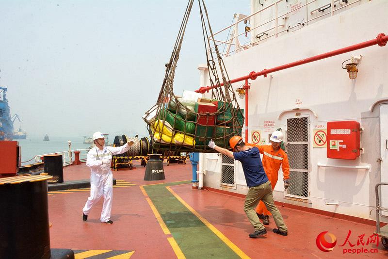 在港口备货时，海员们用吊兜将采购来的食物和生活用品运到船上。（付长超摄）
