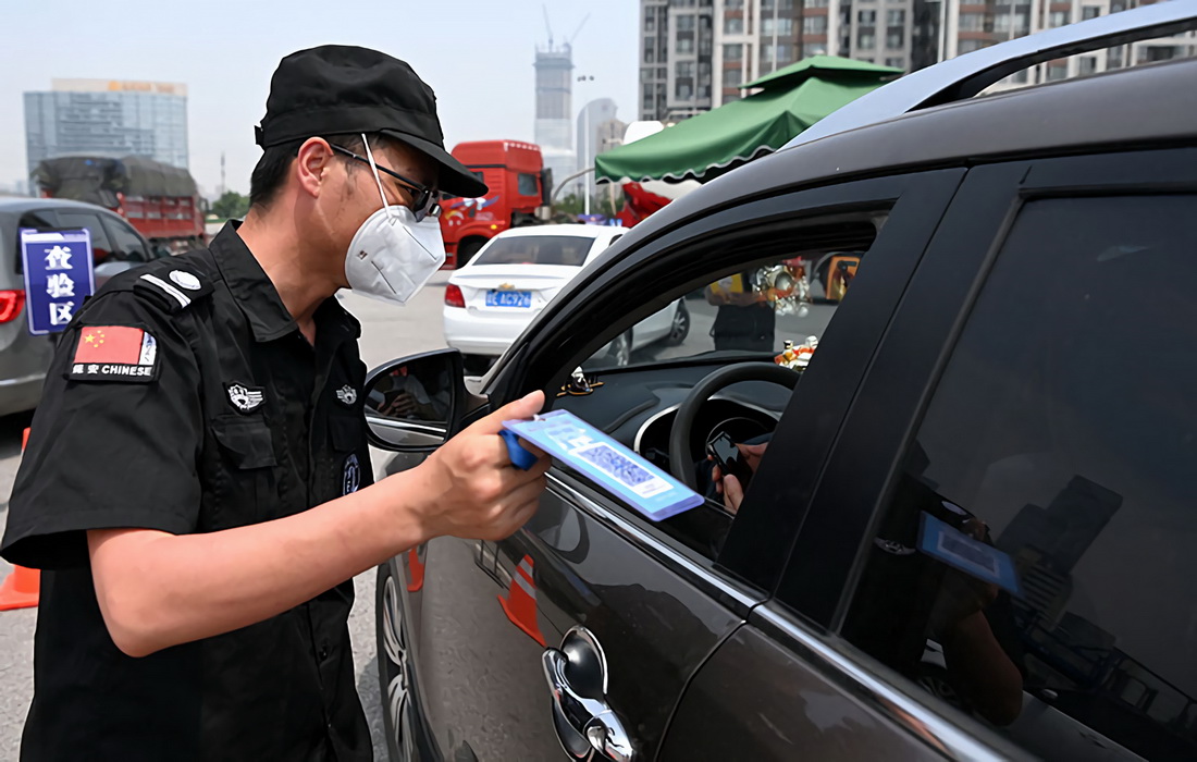 在西安绕城高速高新收费站,工作人员对挡风玻璃上放置有“车辆待查提示牌”的市外行程车辆进行陕西一码通、行程码查验(5月20日摄)。