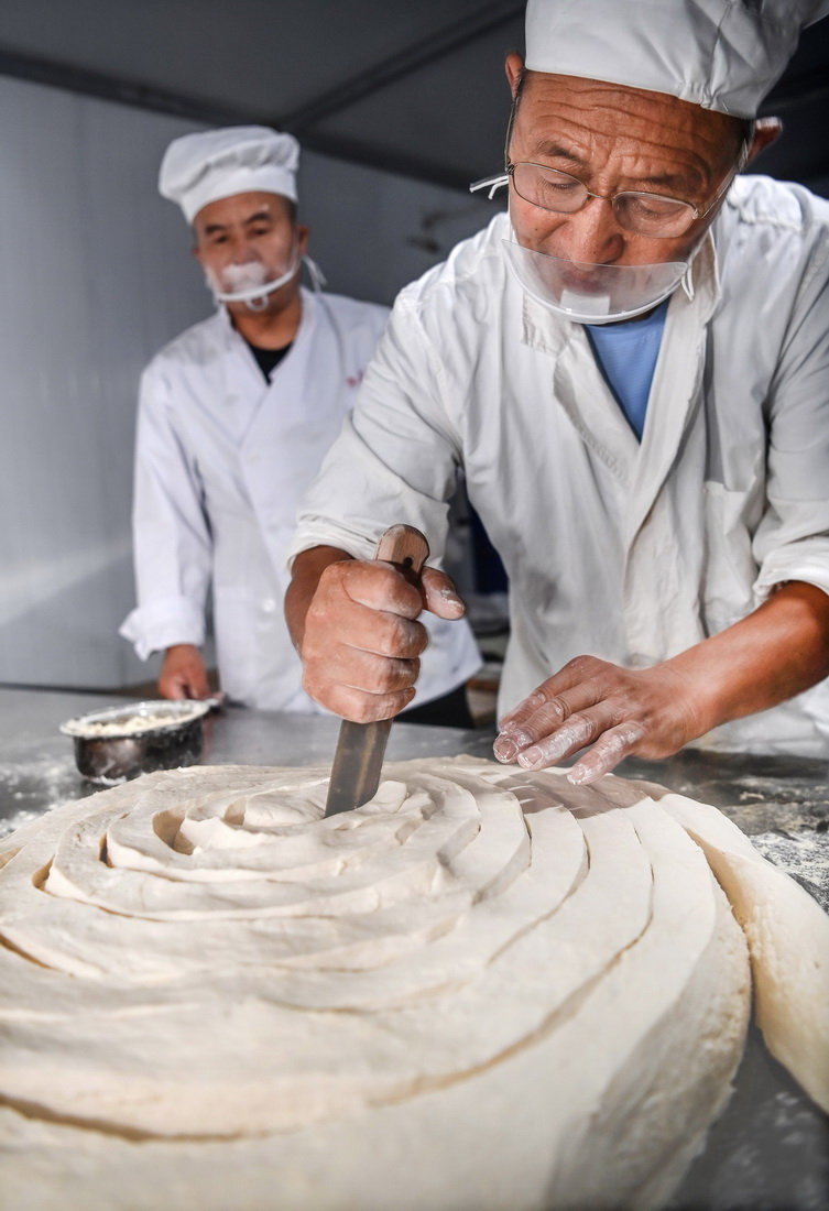 8月16日,李长满(前)向儿子李念平示范操作空心挂面的“开大条”制作工序。