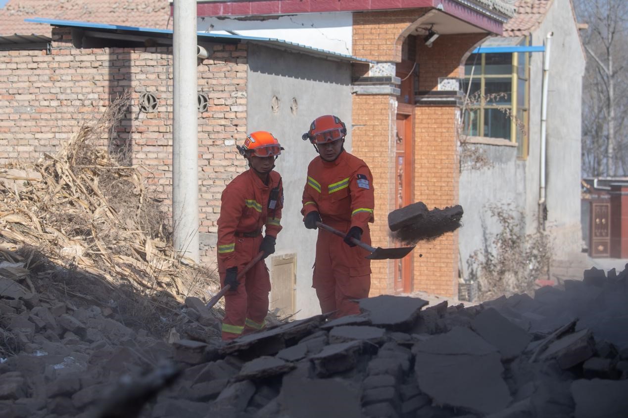 12月21日，在积石山县石塬镇石塬村，消防救援人员正在清理村中道路。人民网记者 翁奇羽摄