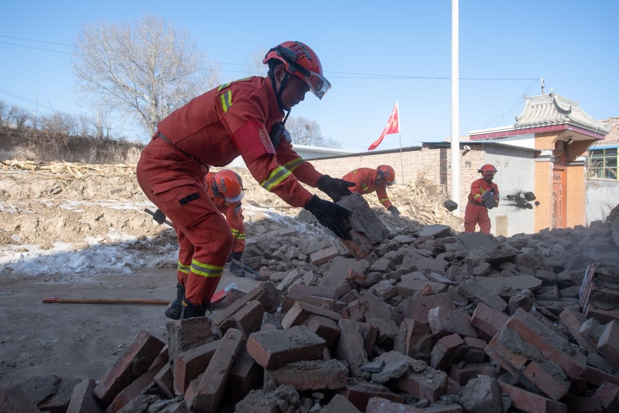 12月21日，在积石山县石塬镇石塬村，消防救援人员正在清理村中道路。人民网记者 翁奇羽摄