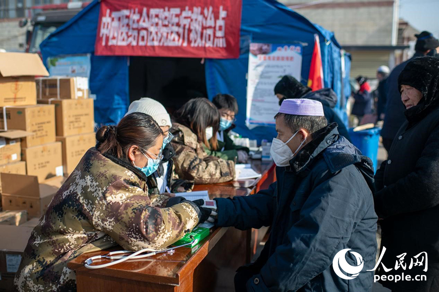 12月22日，在积石山县大河家镇大河村安置点的医疗救治点，医生正在为群众进行医疗问诊。人民网记者 翁奇羽摄