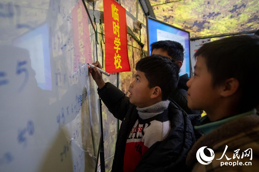 12月22日，在积石山县大河家镇大河村安置点，陆军76集团军某旅搭建的“临时学校”内，小学生正在做题学习。人民网记者 翁奇羽摄