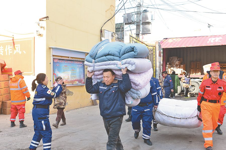 12月23日，甘肃省积石山县石塬镇便民服务中心，救援人员正在卸运救灾物资。 　　本报记者 陈 斌摄