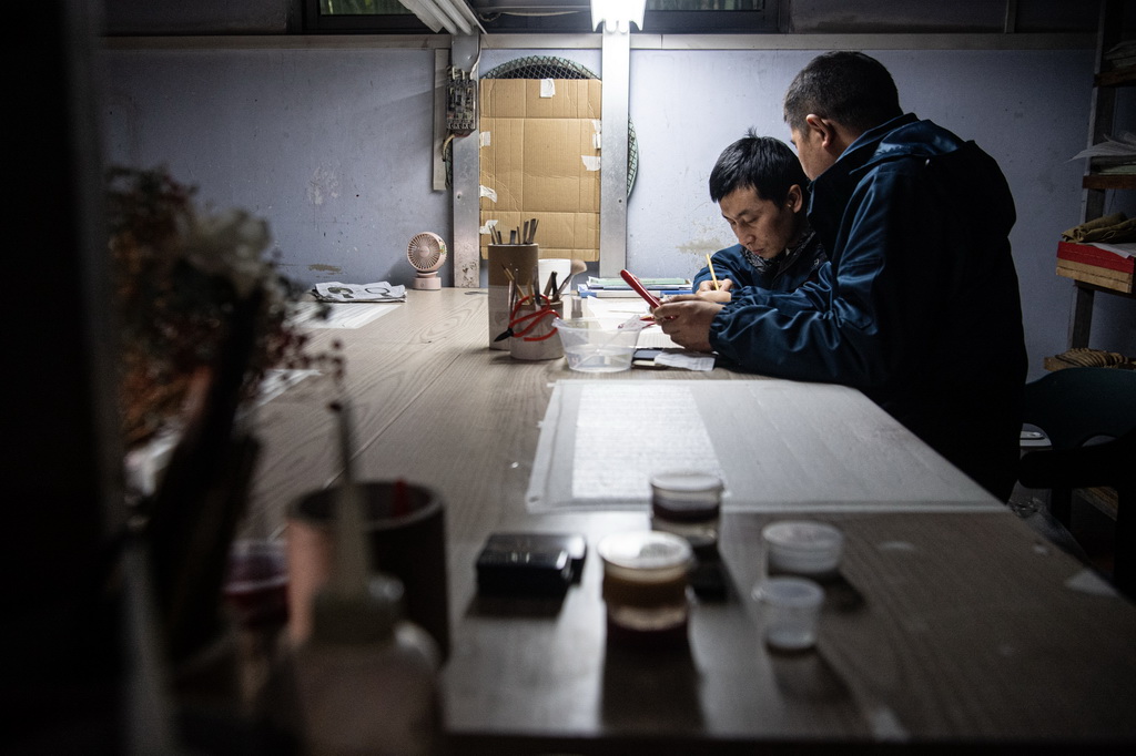 邪在重庆万州谭木匠木梳非遗工坊内，崔国文（右）邪在师傅俞达洪的联结高停言年夜漆工艺创做（1月5日摄）。