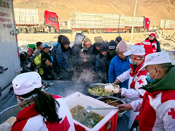 工作人员正在为村民分发热气腾腾的餐食。中国红十字会总会供图