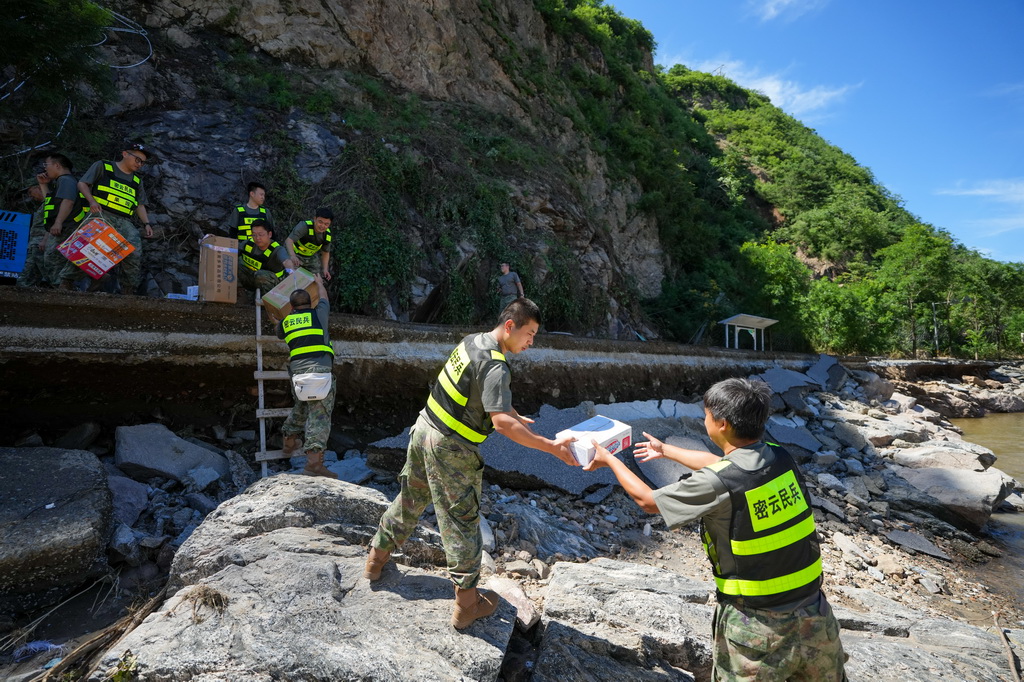 7月30日，在密云区冯家峪镇三岔口村，救援人员为村民运送生活物资。