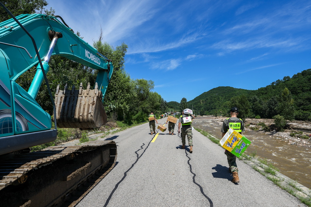 7月30日，在密云区冯家峪镇，救援人员为道路被阻断的村庄运送生活物资。