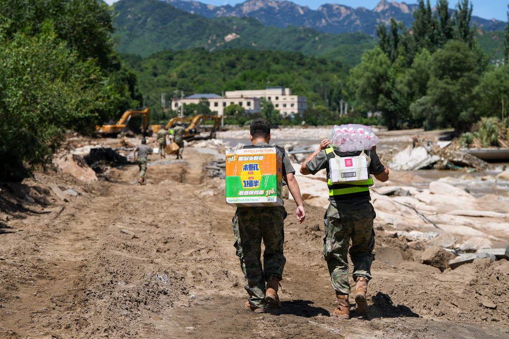7月30日，在密云区冯家峪镇，救援人员为道路被阻断的村庄运送生活物资。