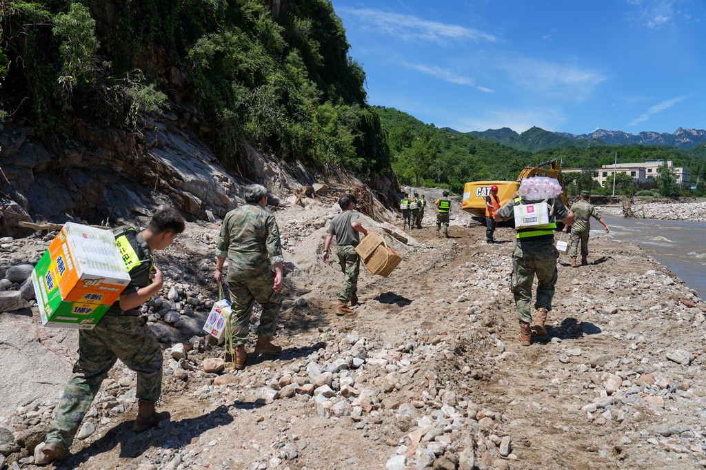 7月30日，在密云区冯家峪镇，救援人员为道路被阻断的村庄运送生活物资。