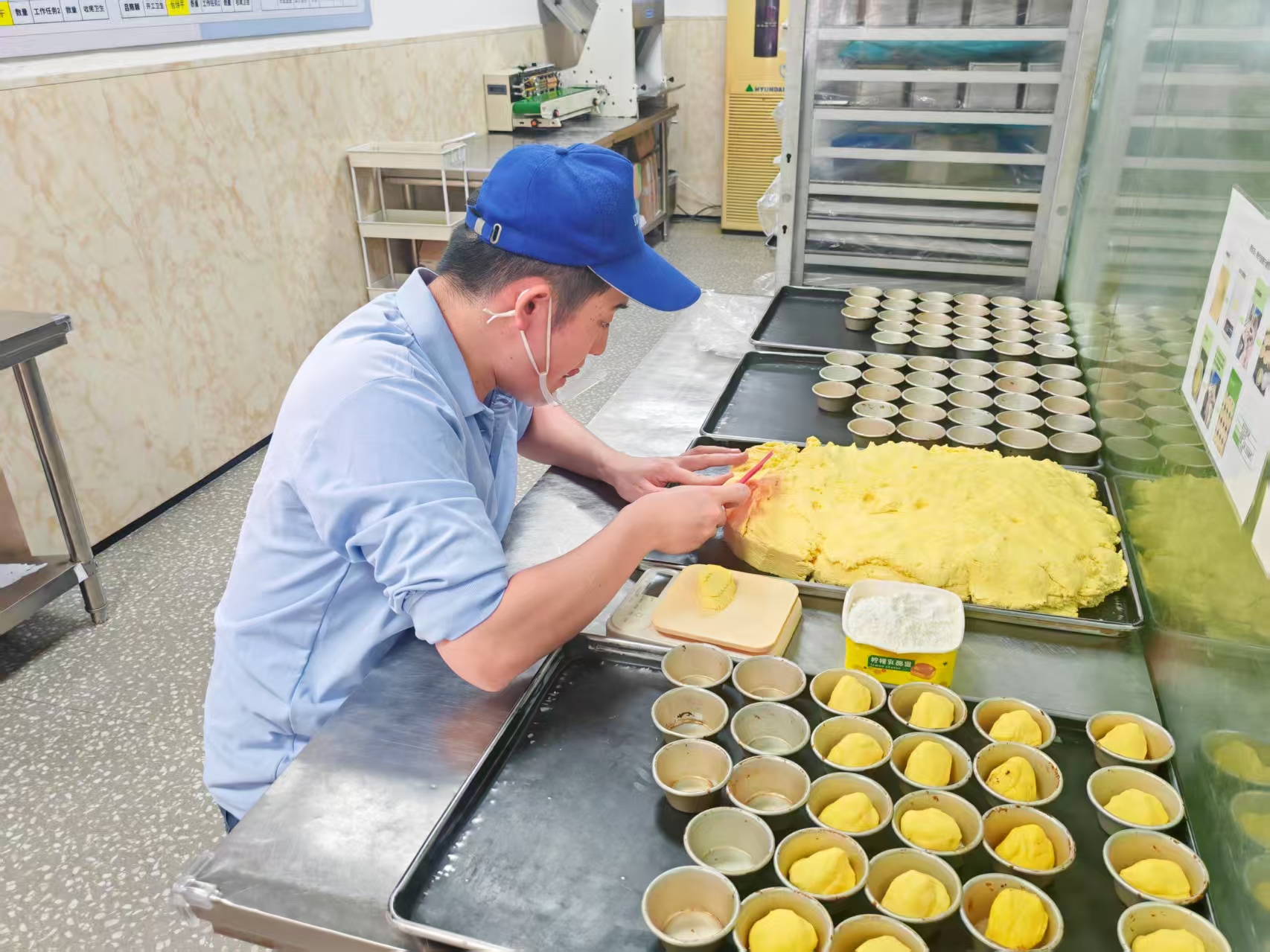 孤独症员工戴着口罩，用干净的双手正在认真制作蛋挞皮。人民网记者 王子锋摄