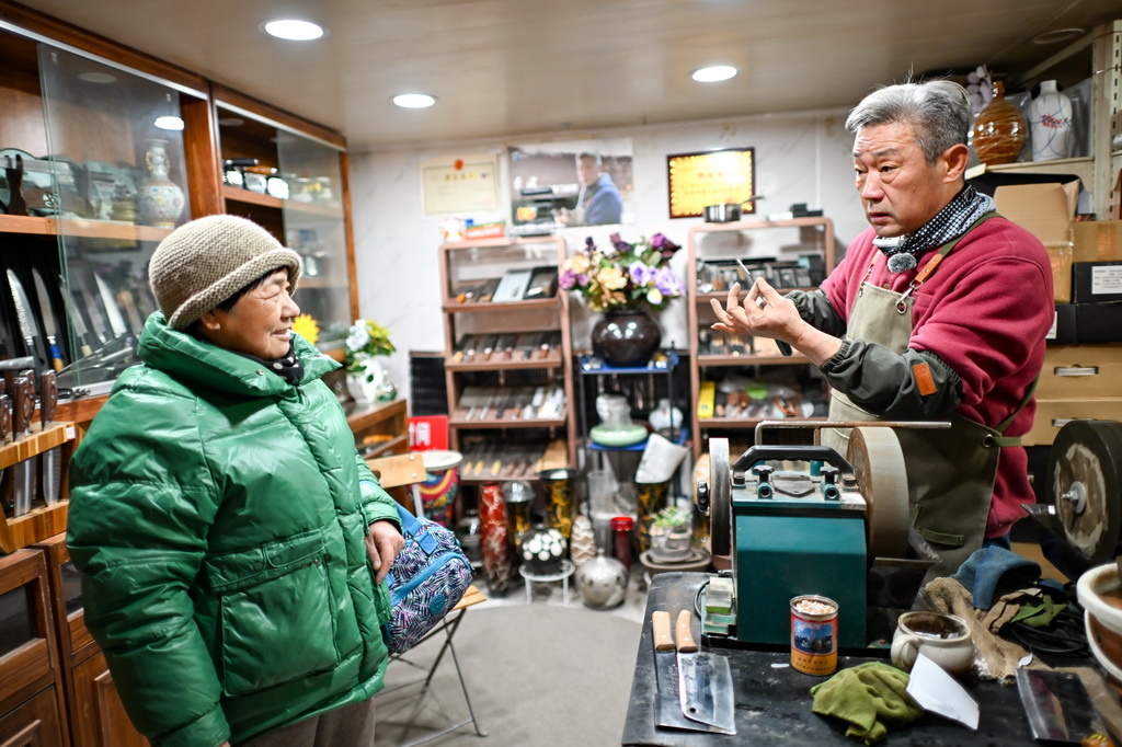 12月9日，商户（右）在为顾客介绍刀具。新华社记者 张铖 摄