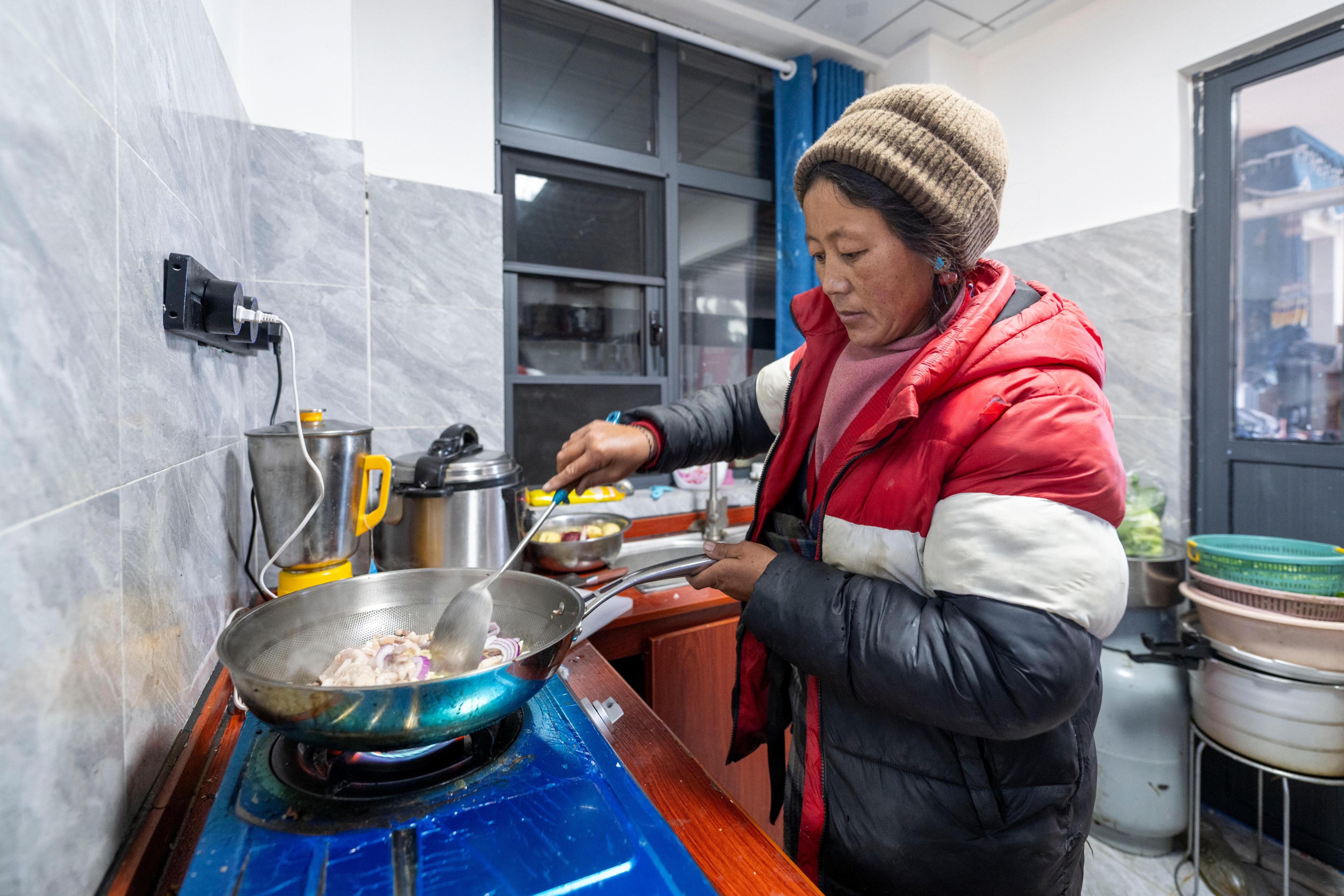 2025年12月11日,在西藏定日县长所乡古荣村,村民塔决在新家宽敞明亮的厨房中准备午饭。人民网记者 翁奇羽摄