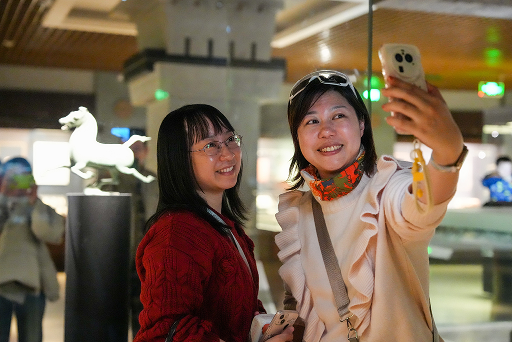 1月26日晚，在甘肃省博物馆二楼丝绸之路文明展厅，观众与东汉铜奔马（复制品）自拍合影。