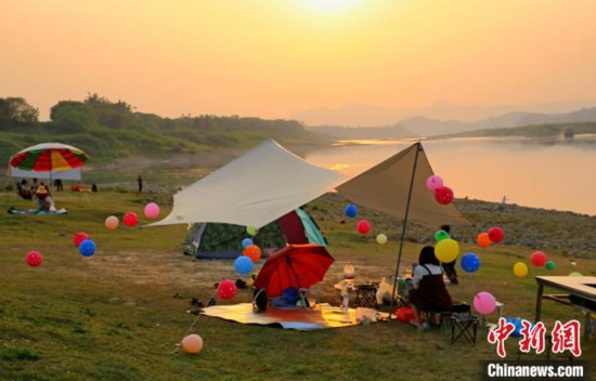 在沿江的露营地上，出游的市民将帐篷进行个性化装扮。　蒙鸣明 摄