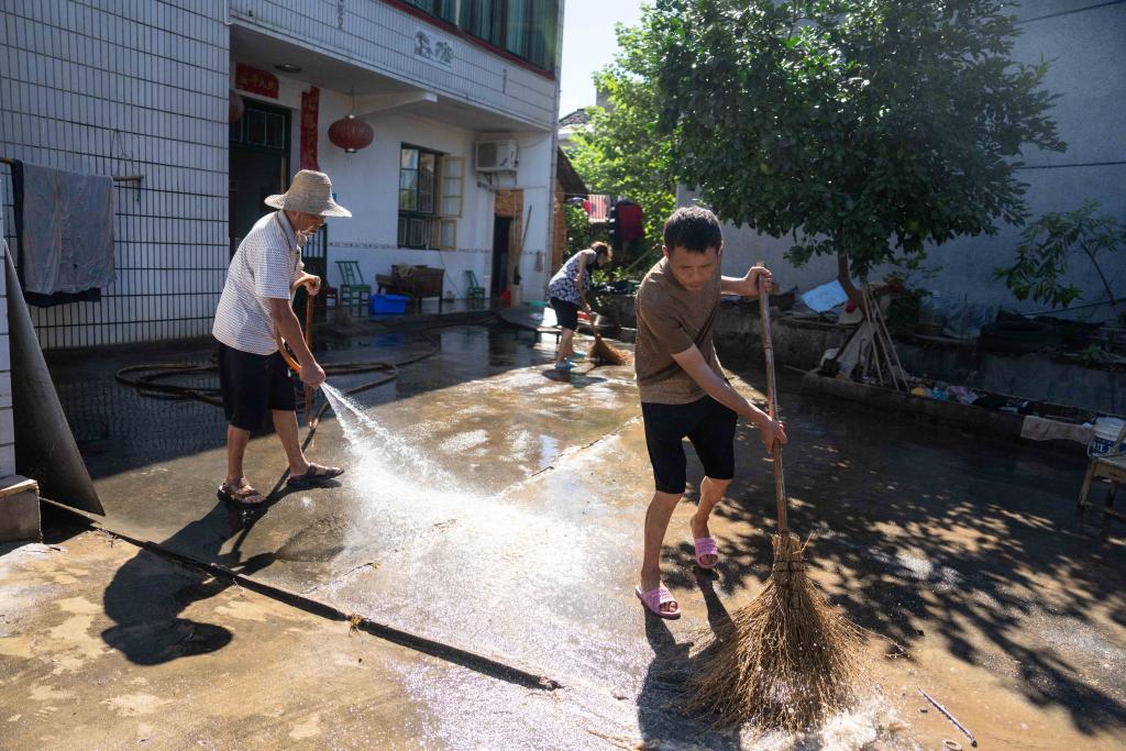 7月31日，在湘潭县河口镇华中村，村民在清扫房屋前坪里的淤泥。新华社记者陈思汗 摄