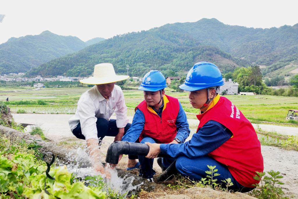 国家电网陕西省平利县供电公司党员服务队在陕西平利县秋河村帮助农户调试抽水水泵。（陈思源 摄）